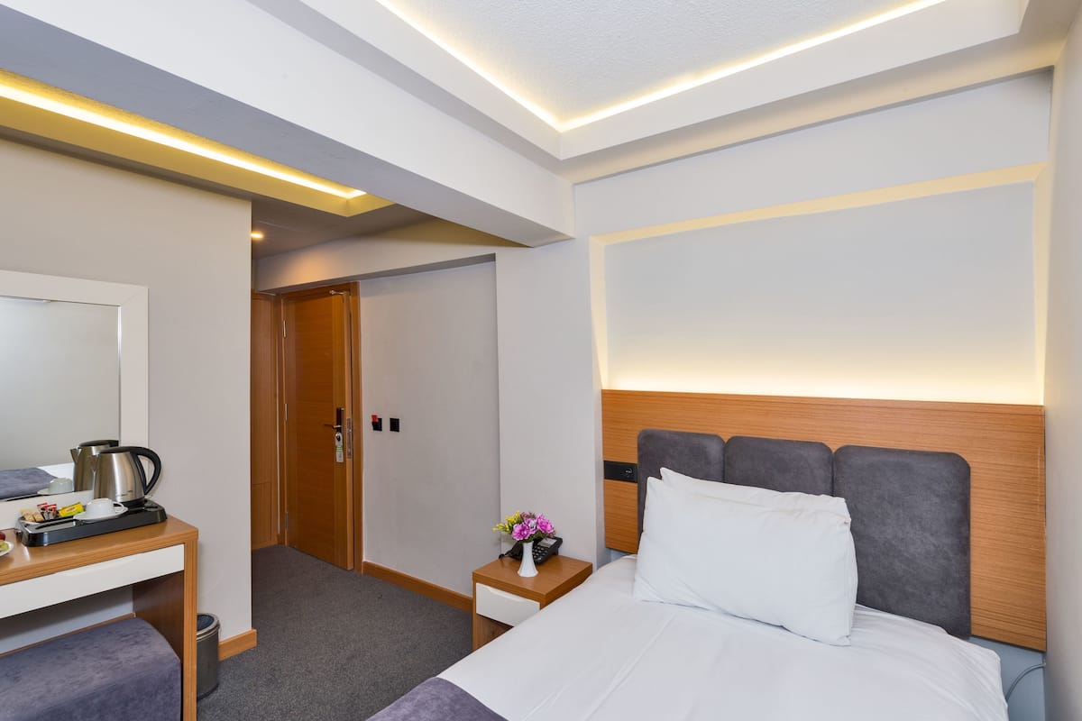 Habitación de hotel con cama, mesita de noche y escritorio con silla. Se ve una puerta que da a otra habitación.
