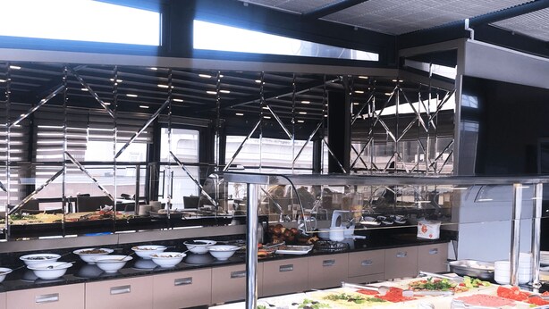 A modern kitchen with stainless steel appliances, a buffet area with various food items, and a glass enclosure for hot dishes. - Bergama Hotel (Istanbul)