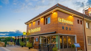 A hotel named "Le Belvédère" with a bar and restaurant. It features a wooden facade, outdoor seating, and a view of the sky. - Le Belvedere (Rocamadour)