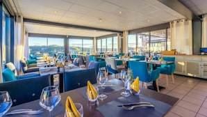 A restaurant with tables set for dining, large windows offering a view, and a modern interior design. - Le Belvedere (Rocamadour)