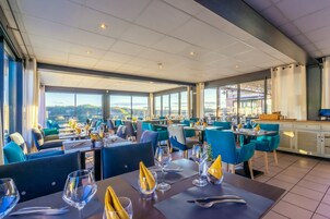 A restaurant with tables set for dining, large windows offering a view, and a modern interior design.