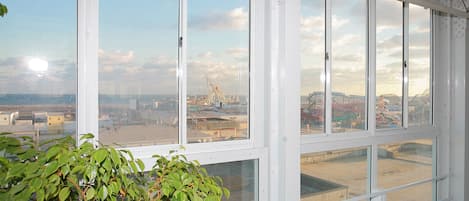 Una habitación con grandes ventanales que ofrecen vistas a un paisaje urbano y una noria.