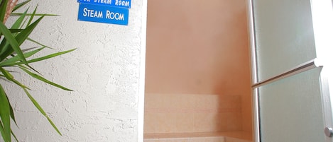 A steam room with a sign indicating age restriction, a white chair, and a tiled floor.