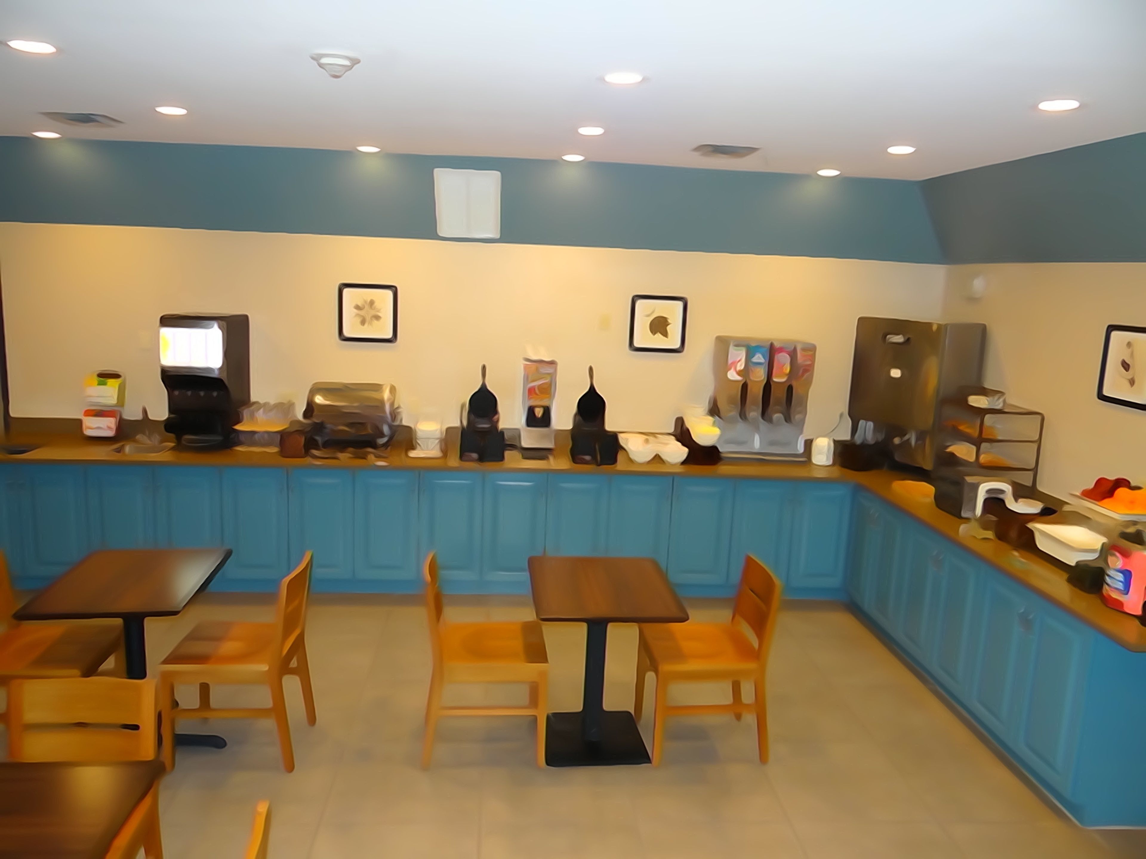A cafe with a blue counter, coffee machines, and wooden tables and chairs.