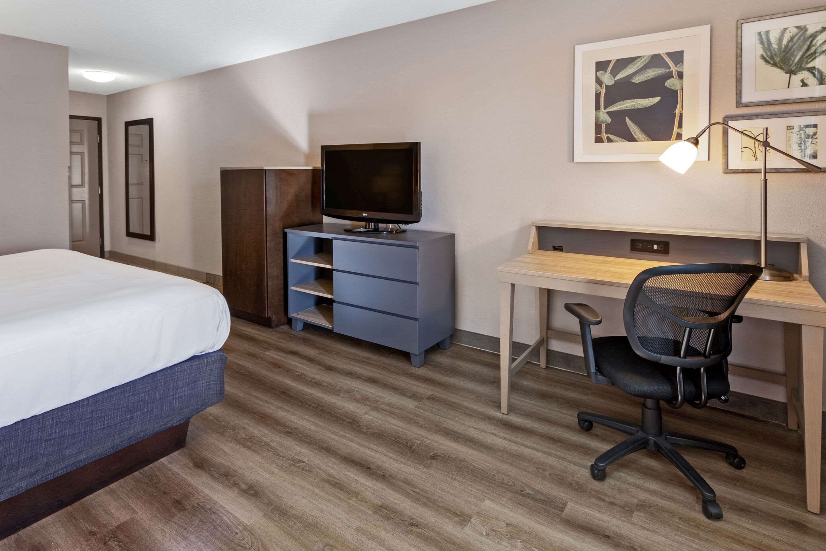 Una habitación de hotel con una cama, un escritorio con computadora, un televisor y una silla.