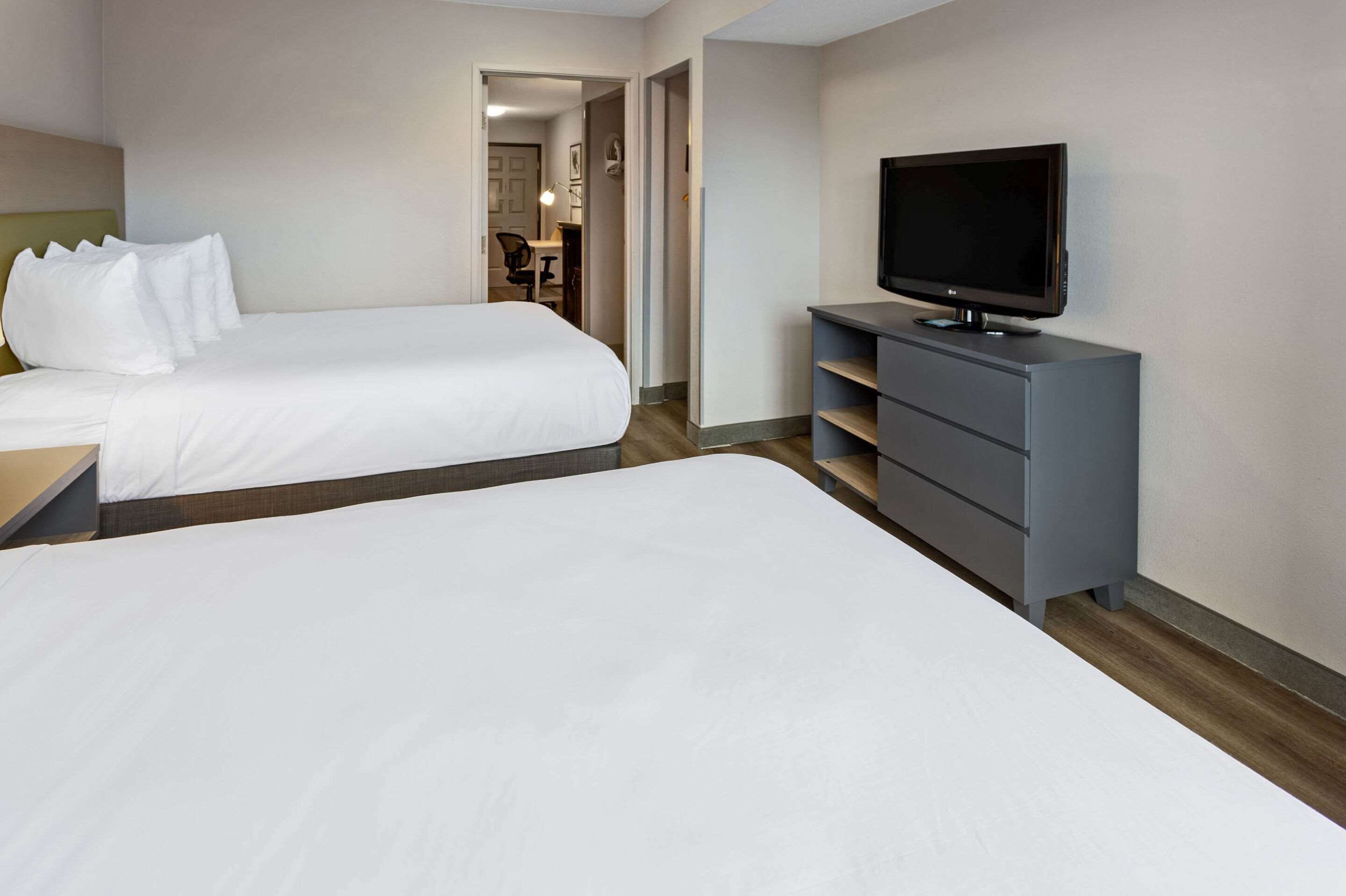 A hotel room with two beds, a TV on a dresser, and a desk with a chair.