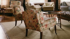 A cozy room with wooden ceilings, floral-patterned armchairs, a leather sofa, and a small table. - Chebeague Island Inn (Chebeague Island)