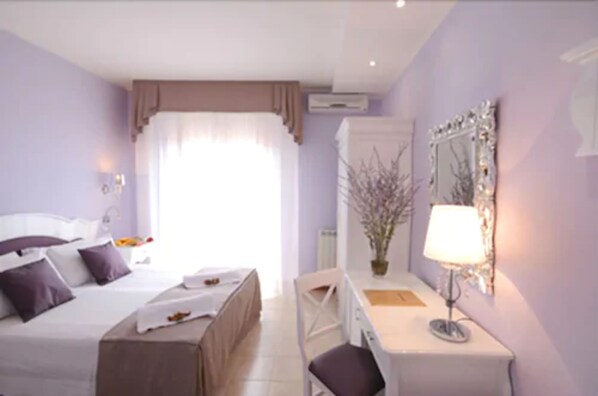 A hotel room with a bed, bedside table, chair, desk, and a mirror. - Hotel I Due Cigni (Montepulciano)