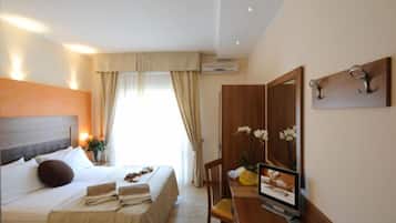 A hotel room with a bed, a desk, a chair, a TV, and a mirror.