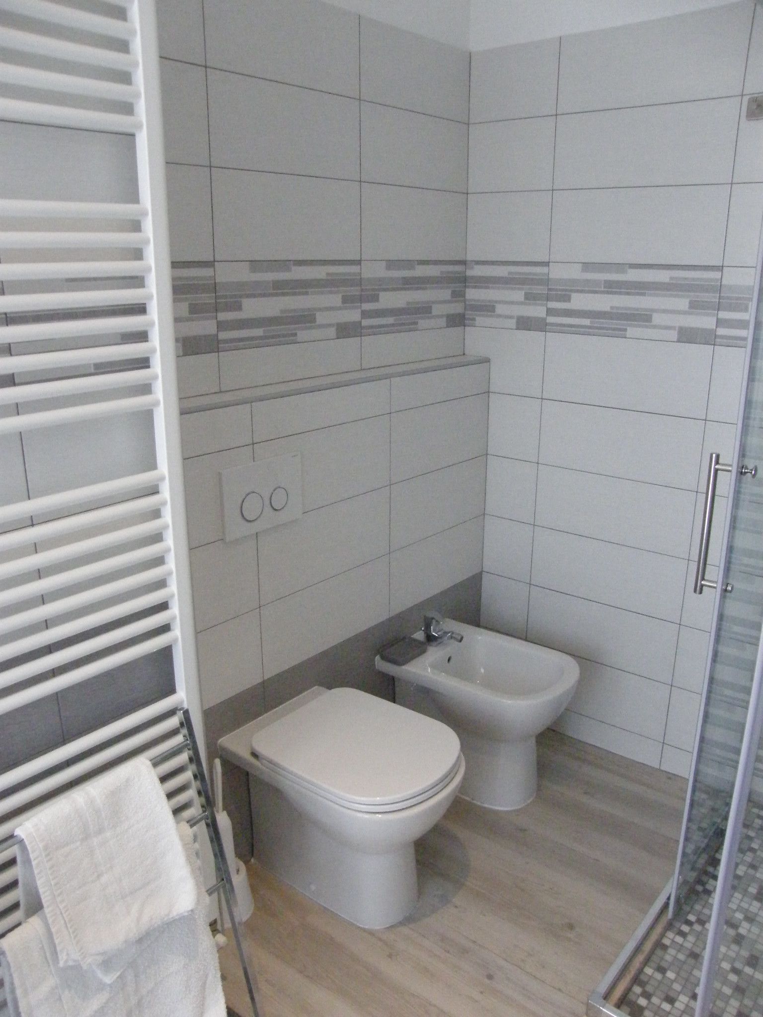 A small bathroom with a toilet, bidet, and towel rack.
