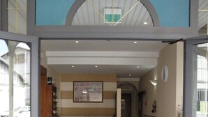 Una entrada con mostrador de recepción, piso de baldosas y un reloj en la pared.