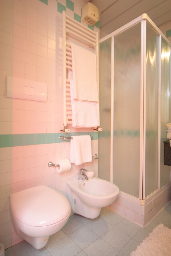 A bathroom with a toilet, bidet, and a glass-enclosed shower stall. - Hotel Stefan (Gatteo)