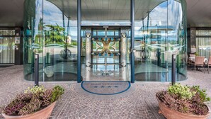 A hotel entrance with a glass facade, a central decorative element, and a seating area visible through the glass. - Best Western Hotel Turismo (San Martino Buon Albergo)