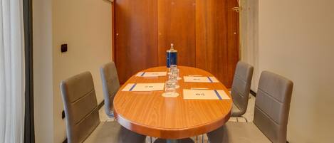 A conference room with a wooden table, four chairs, and a coat stand.