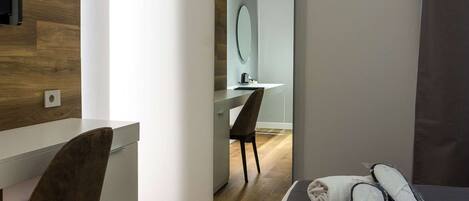 Une chambre d’hôtel moderne avec un mur d’accent en bois, un bureau, une chaise, un lit avec des serviettes et des articles de toilette, et un miroir.