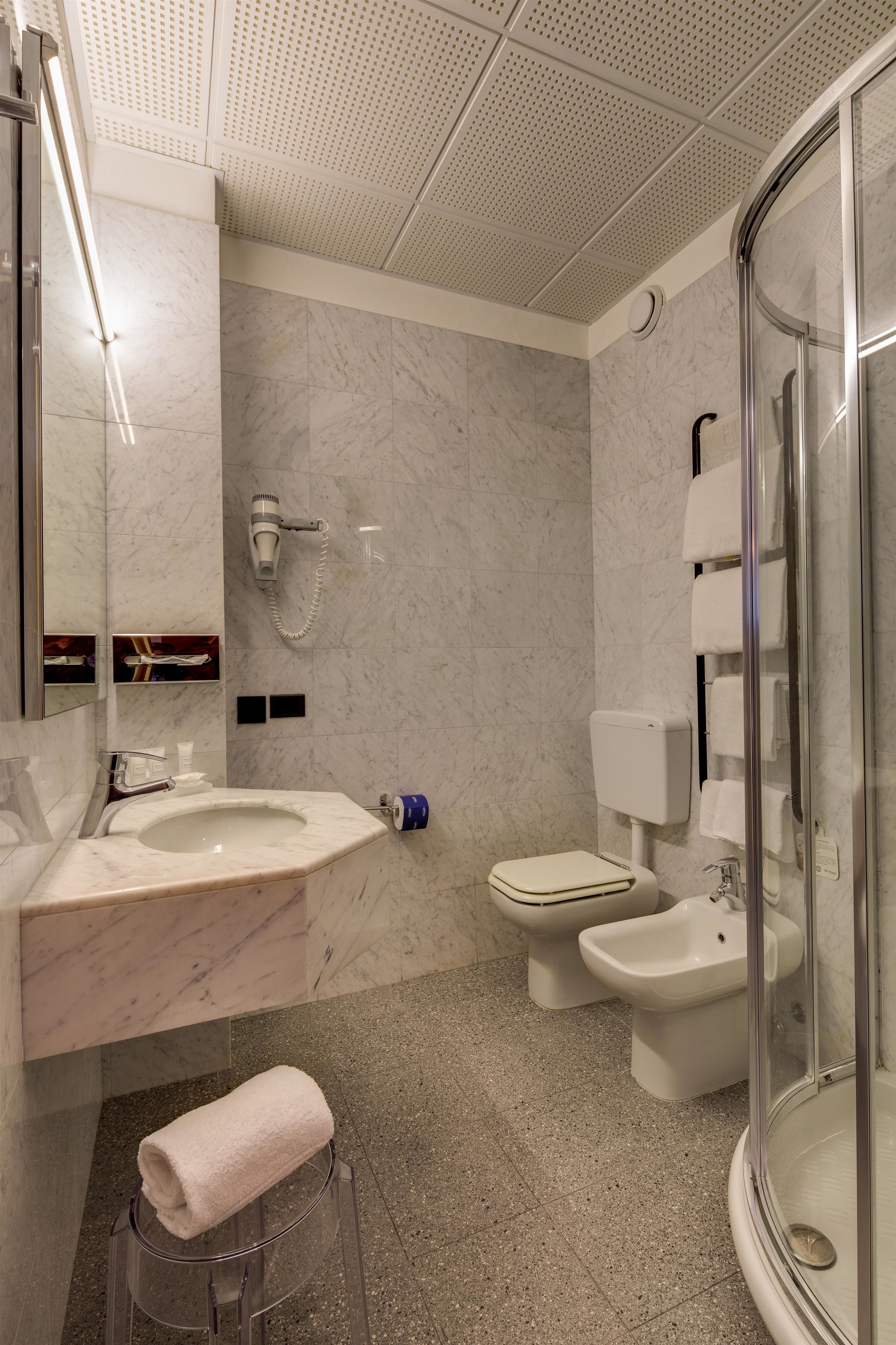 Ein modernes Badezimmer mit Marmorwaschbecken, Toilette, Bidet und einer Duschkabine.