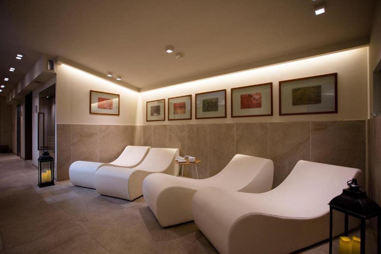 A spa area with two reclining chairs, a wall-mounted picture frame, and a small table with cups.