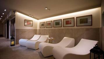 A spa area with two reclining chairs, a wall-mounted picture frame, and a small table with cups.