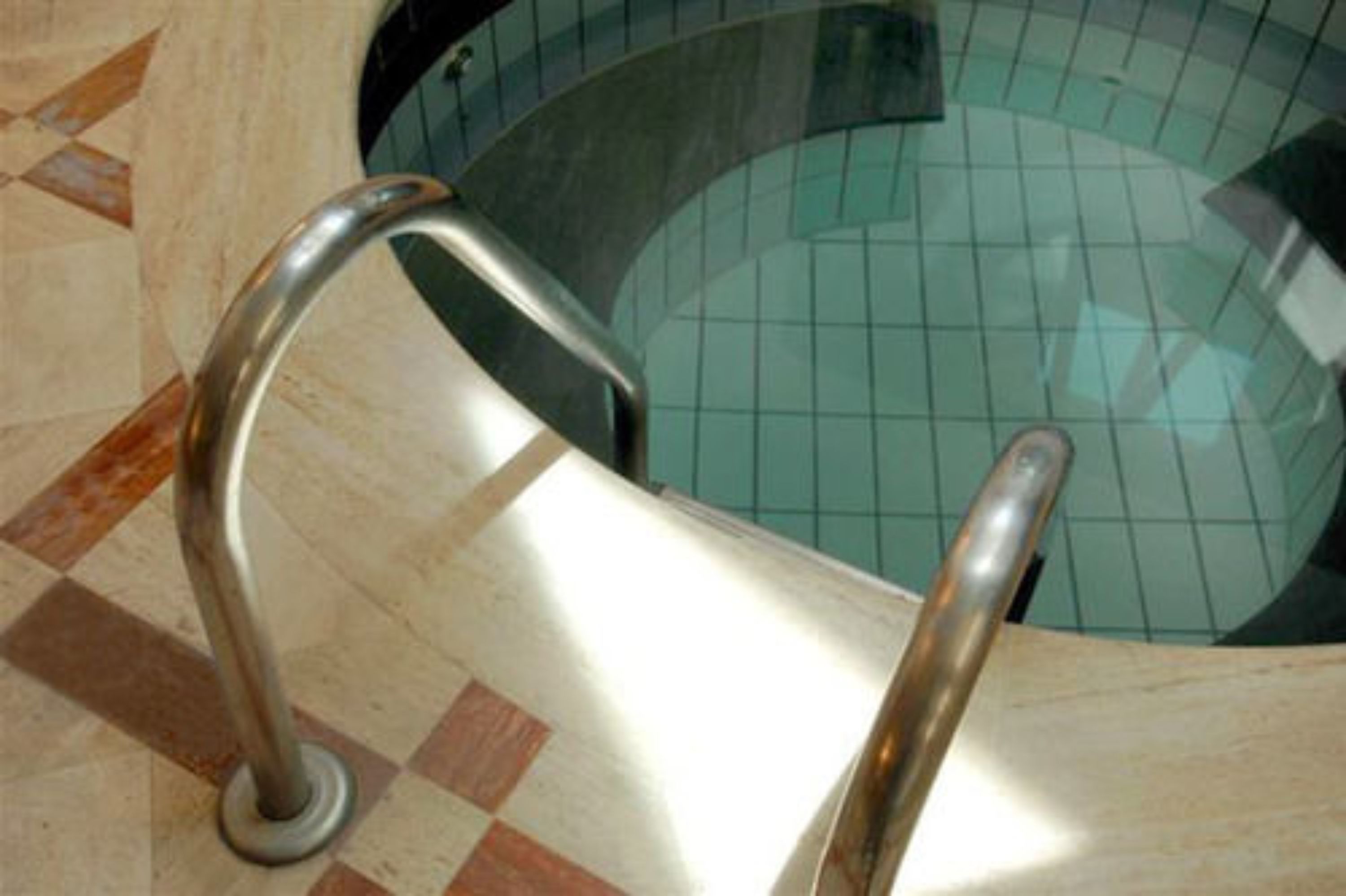 Ein Pool mit Fliesenboden und Metallhandläufen.