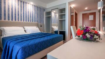 A hotel room with a bed, a desk, a chair, a wardrobe, and a bathroom.