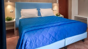 A modern bedroom with a large bed, two bedside tables, and a wooden headboard. - Hotel Martino (Maratea)