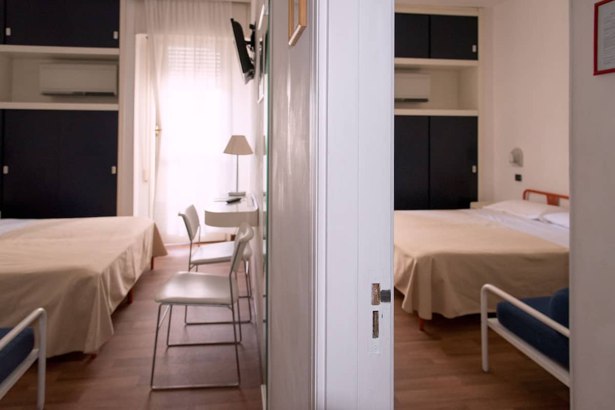 A room with two beds, a desk, and chairs.