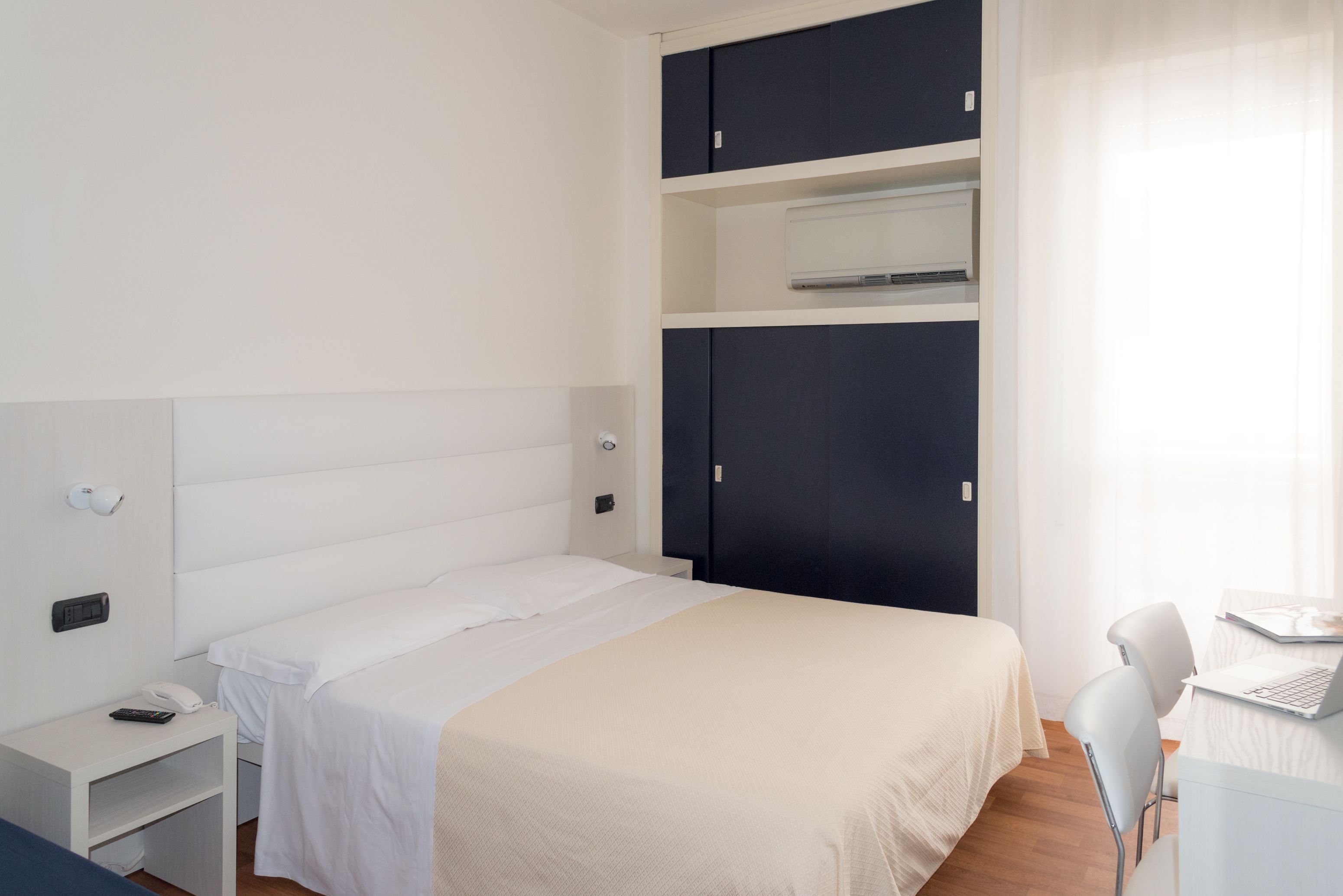 A bedroom with a bed, a desk, a chair, and a wardrobe.