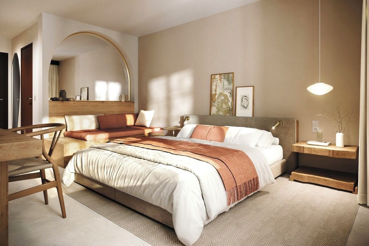 A modern bedroom with a large bed, a desk, and a chair.