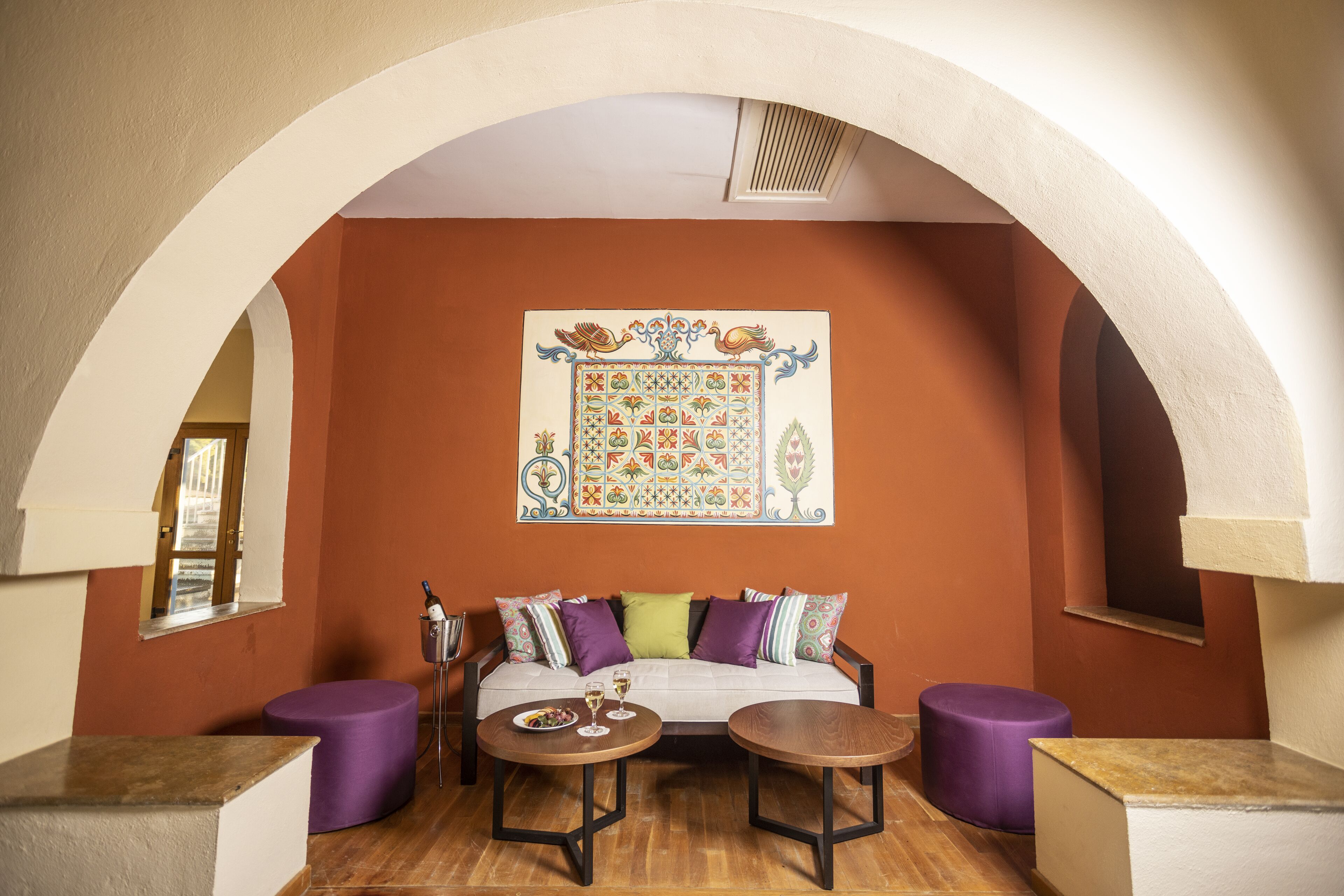 A cozy room with a sofa, two round tables, and a decorative wall piece.