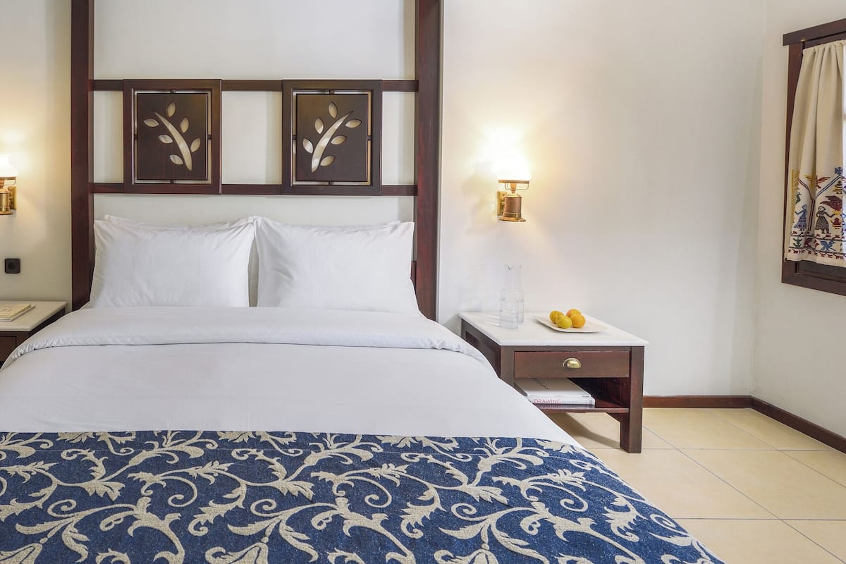 Ein Hotelzimmer mit einem großen Bett, zwei Nachttischen, einem Sessel und dekorativen Wandverkleidungen.