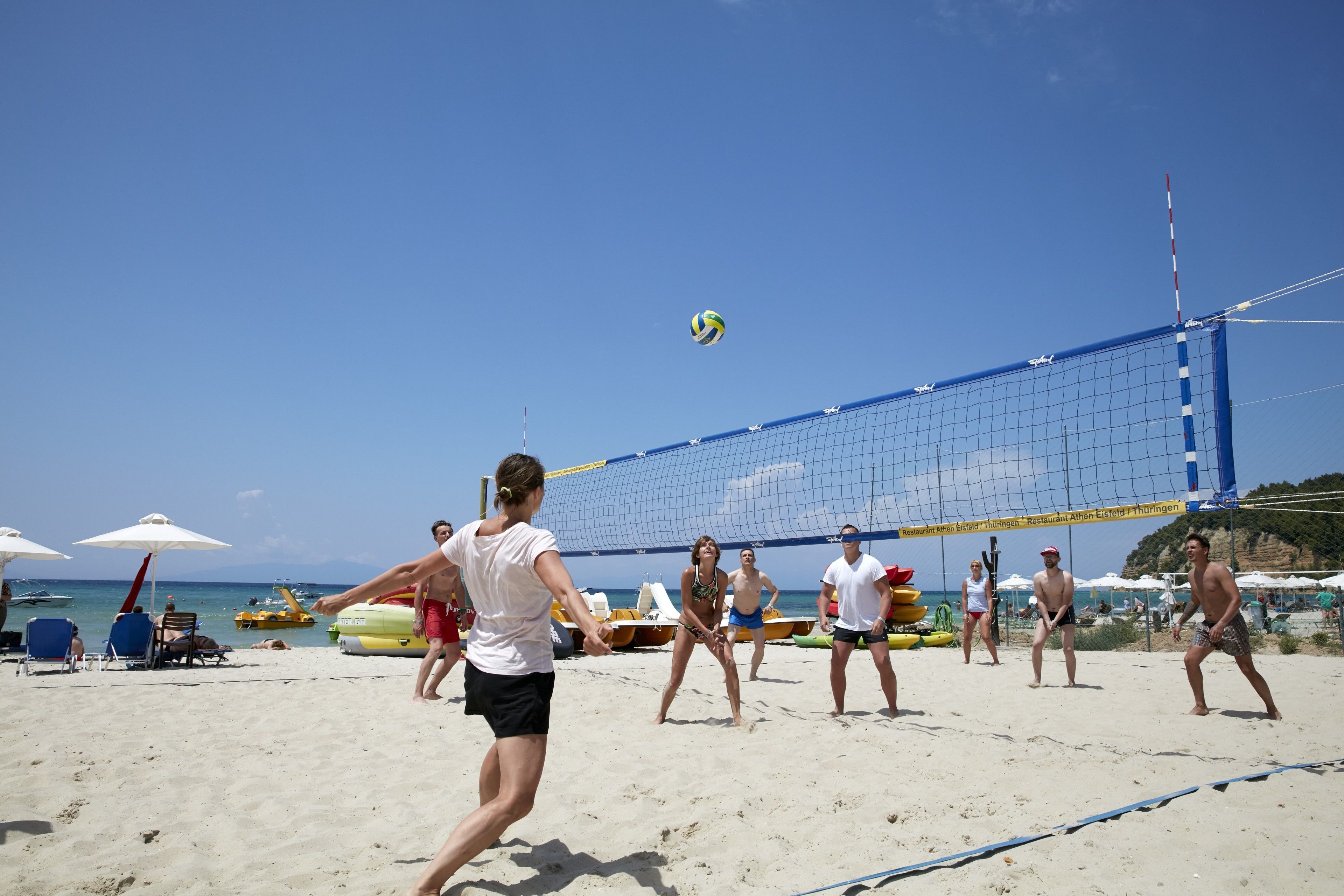 A beach volleyball game in progress with a net and players.