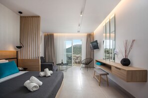 A modern hotel room with a bed, a desk, a chair, a TV, and a balcony with a view.