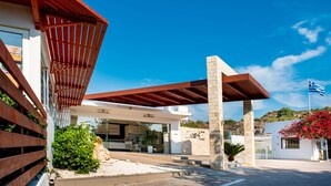 A modern building with a covered entrance, a stone pillar, and a flag. - Zoes Hotel (Rhodes)