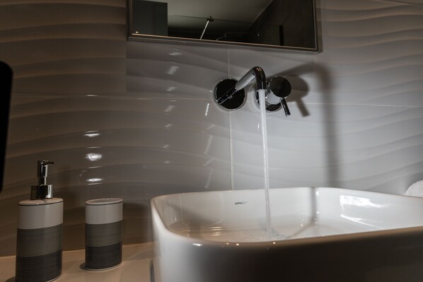 A bathroom with a modern sink, a mirror, and a wall with a wavy pattern. - Zoes Hotel (Rhodes)