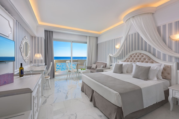 Un dormitorio amplio con una cama grande, una zona de estar con vista al mar y un balcón.