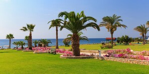 Un resort costero con palmeras, parterres de flores y vistas al mar.
