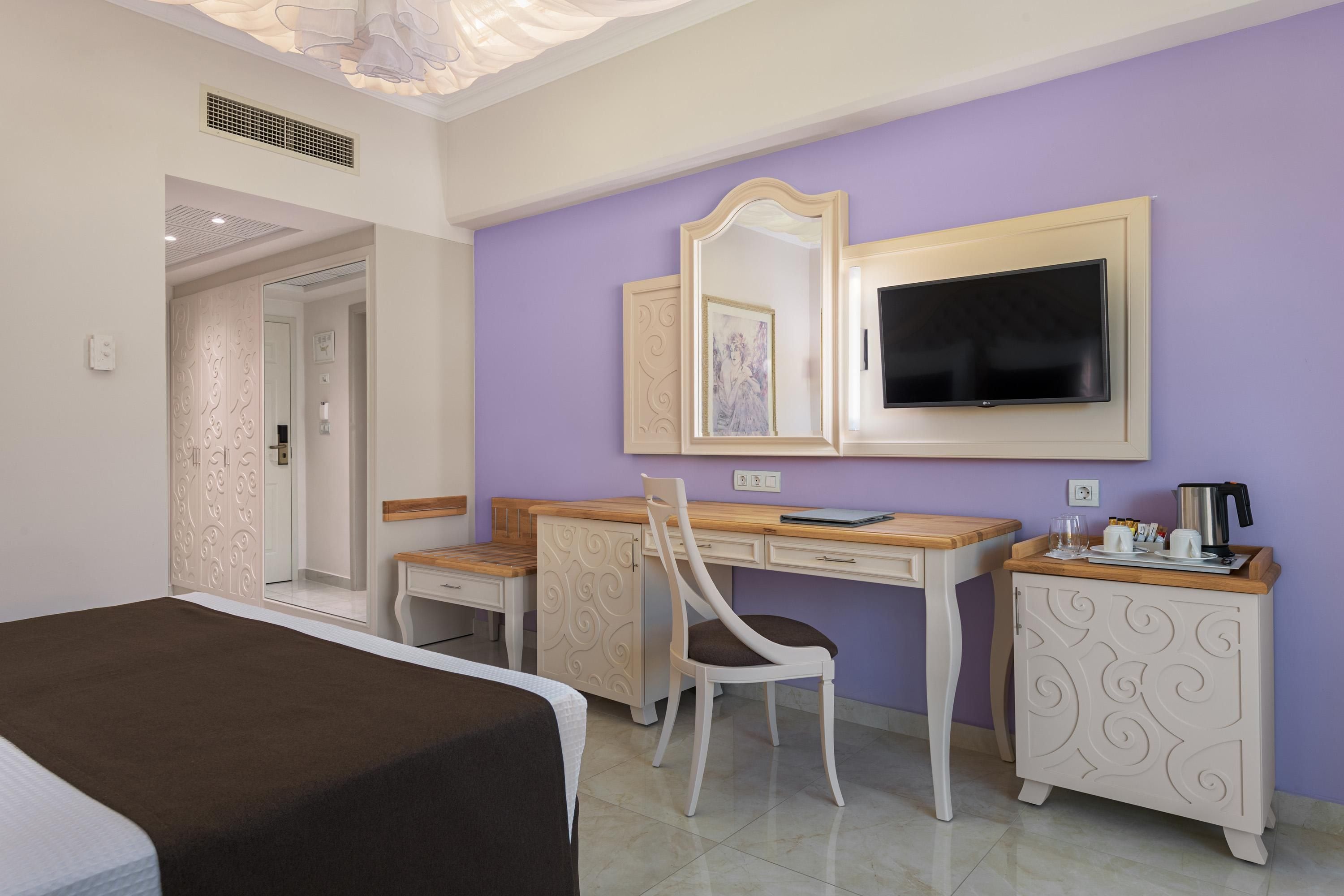 Une chambre d’hôtel comprenant un lit, un bureau, une chaise, une télévision et une armoire.