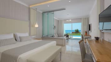 A modern hotel room with a large bed, a dining area, and a view of the ocean.
