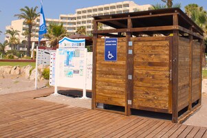 Una estructura de madera señalizada como vestuario con un rótulo de accesibilidad para sillas de ruedas.