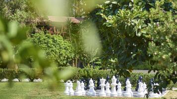 A chessboard set up outdoors with greenery in the background.