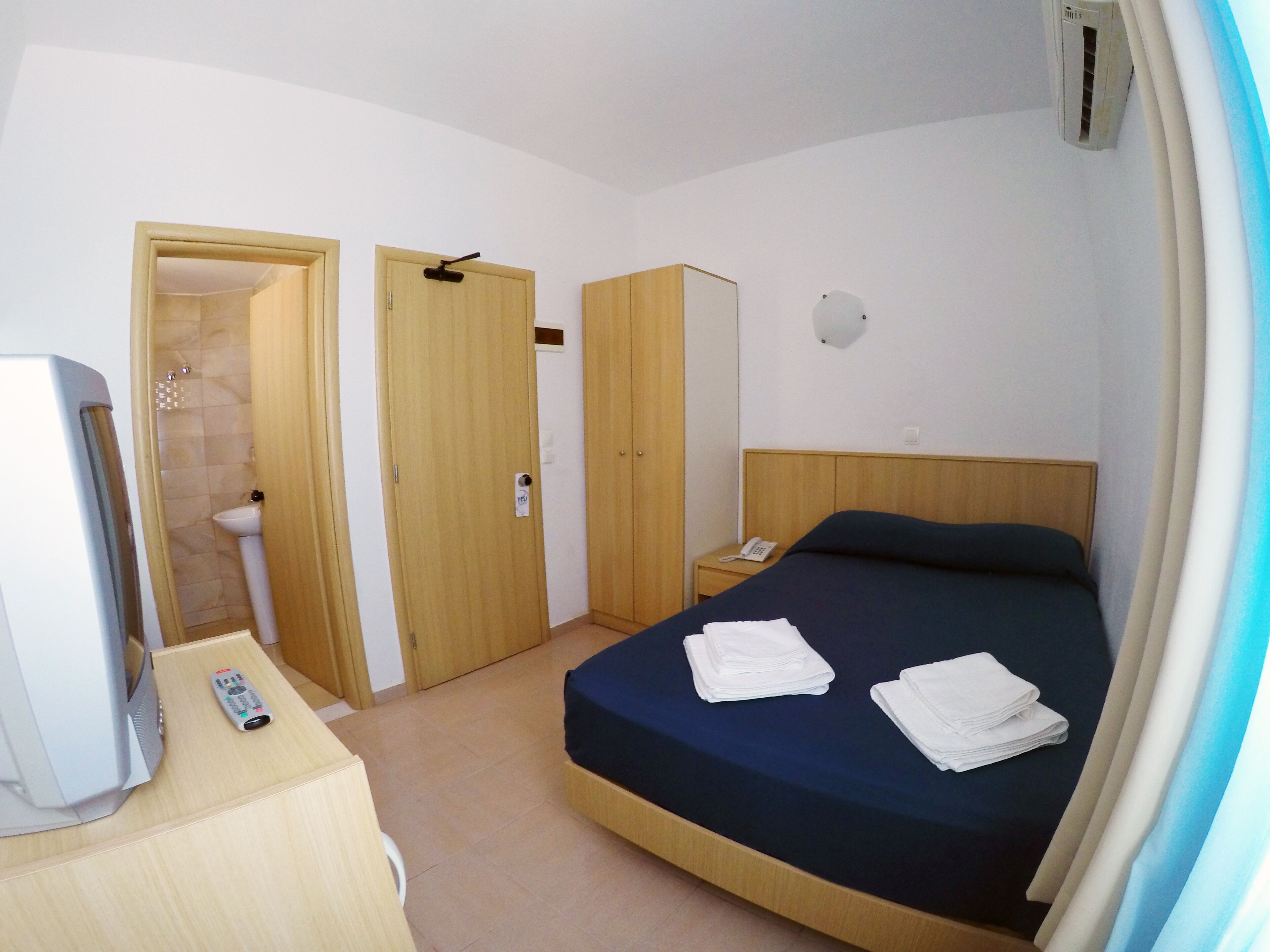 Une chambre d’hôtel avec un lit, une télévision, une armoire et une salle de bain.