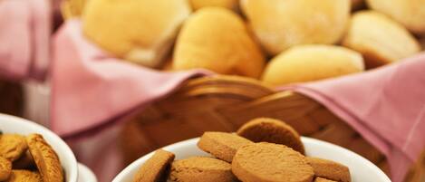 Diversas opciones de panadería, como galletas y pan, expuestas en cuencos y cestas.