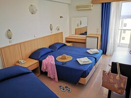 Egy szállodai szoba két ággyal, íróasztallal, tükörrel, telefonnal és egy bőrönddel.