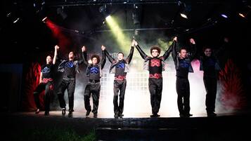 A group of people on a stage with a smoke effect, wearing coordinated outfits with a logo.