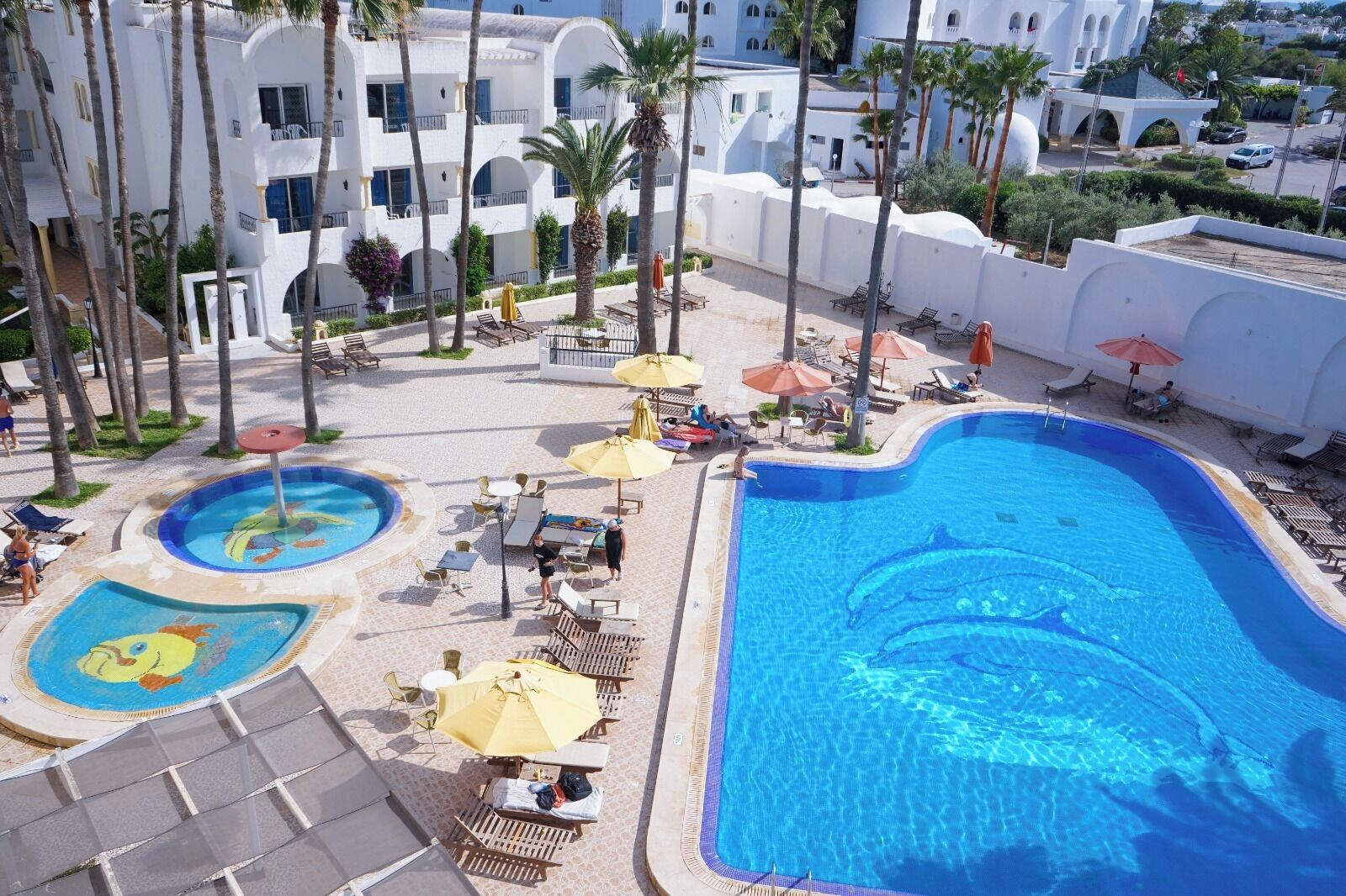 Un resort con varias piscinas, tumbonas y sombrillas.