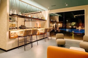 A modern bar area with a pool view, bar stools, and a seating area with a sofa. - Morasol Atlantico (Pajara)