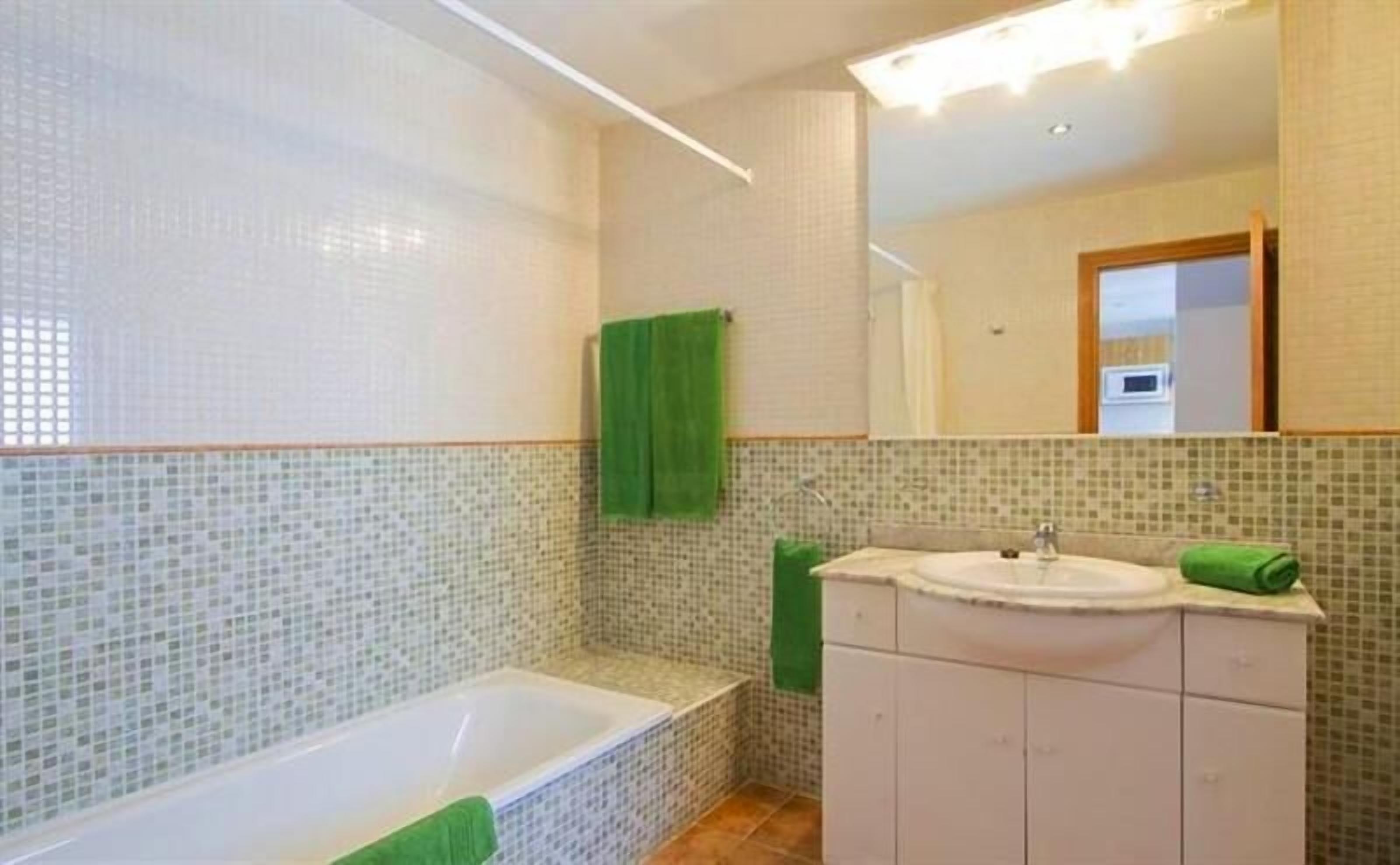 A bathroom with a bathtub, a sink, and a mirror.
