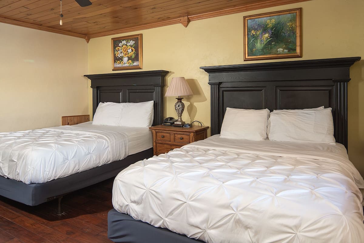Two twin beds with dark wooden headboards, white bedding, and a small bedside table with a lamp.