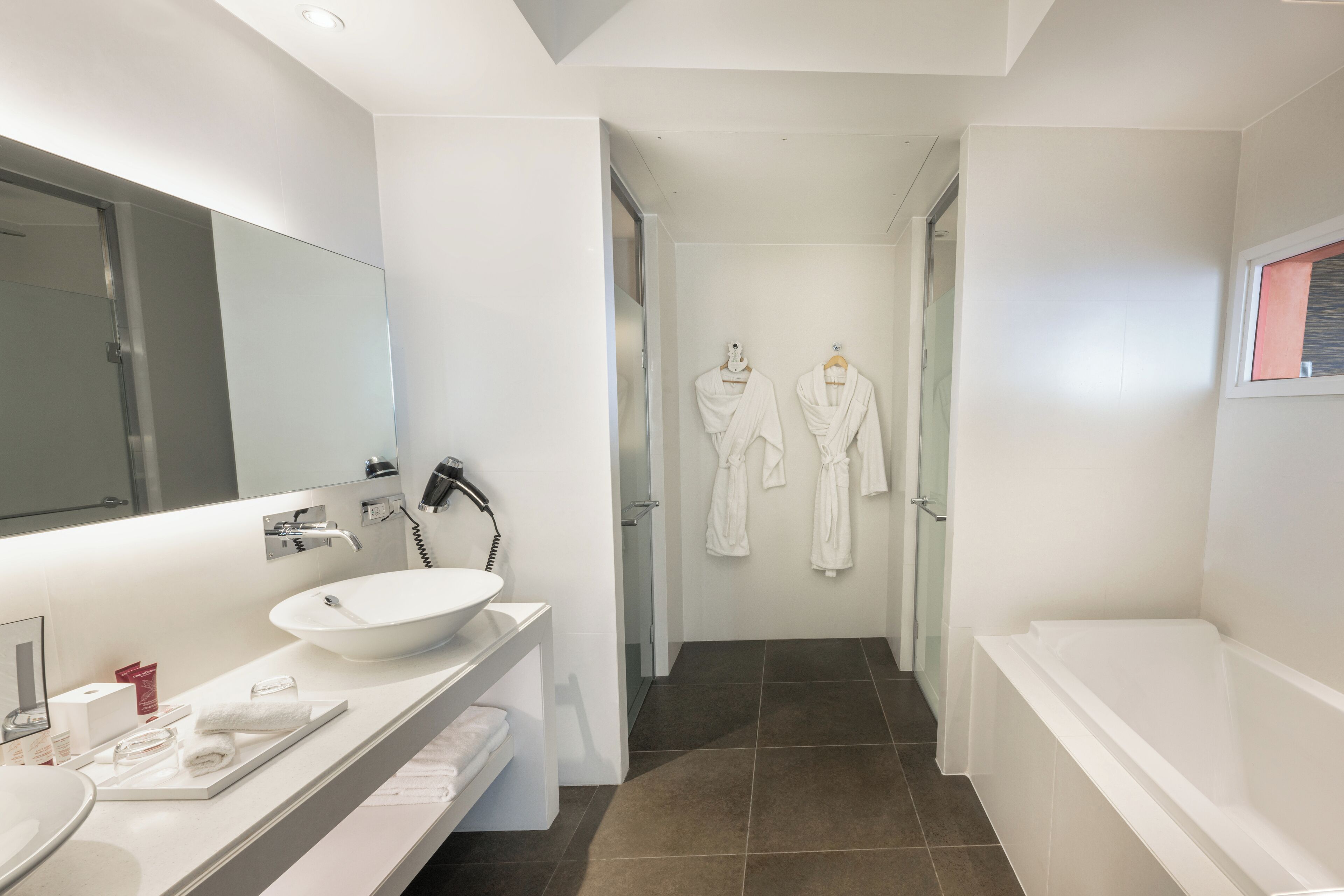 Un bagno moderno con uno specchio grande, un lavandino bianco e una vasca da bagno.