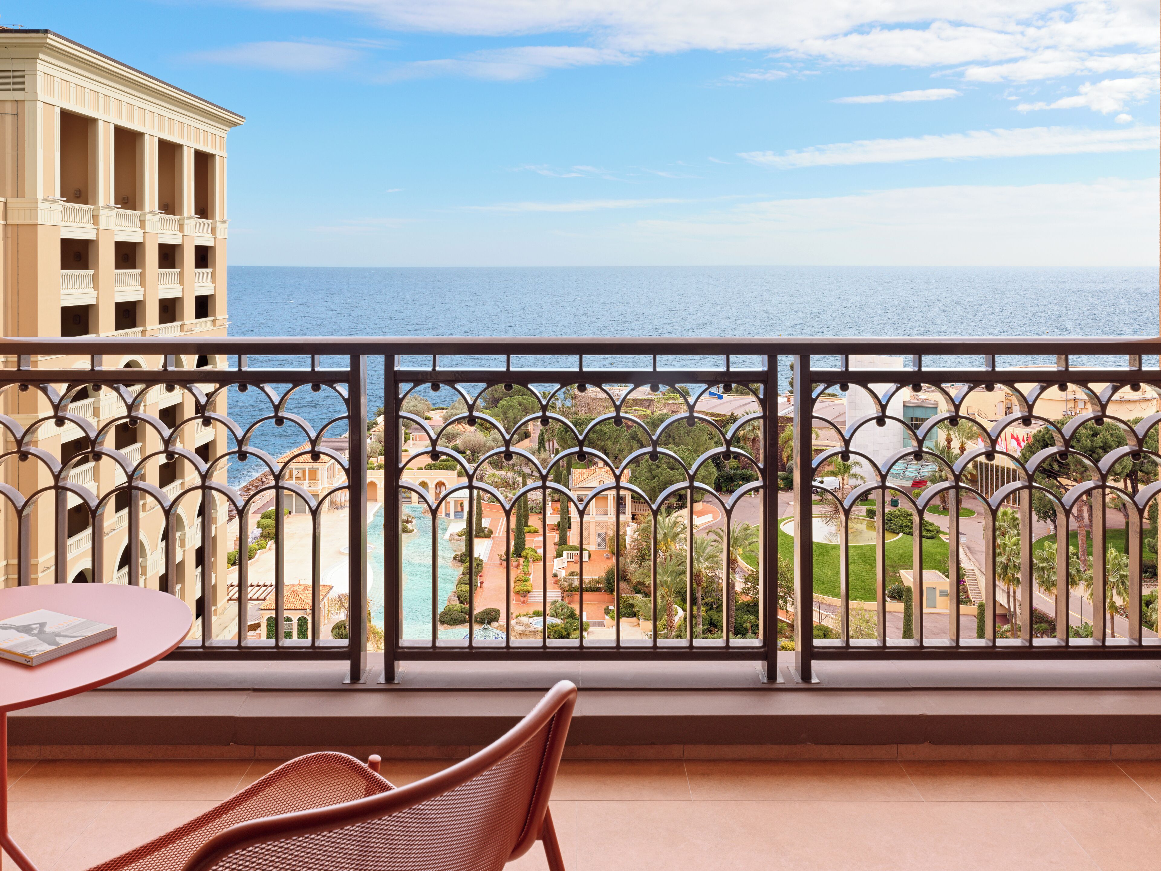 A balcony with a view of the sea and a building with columns.